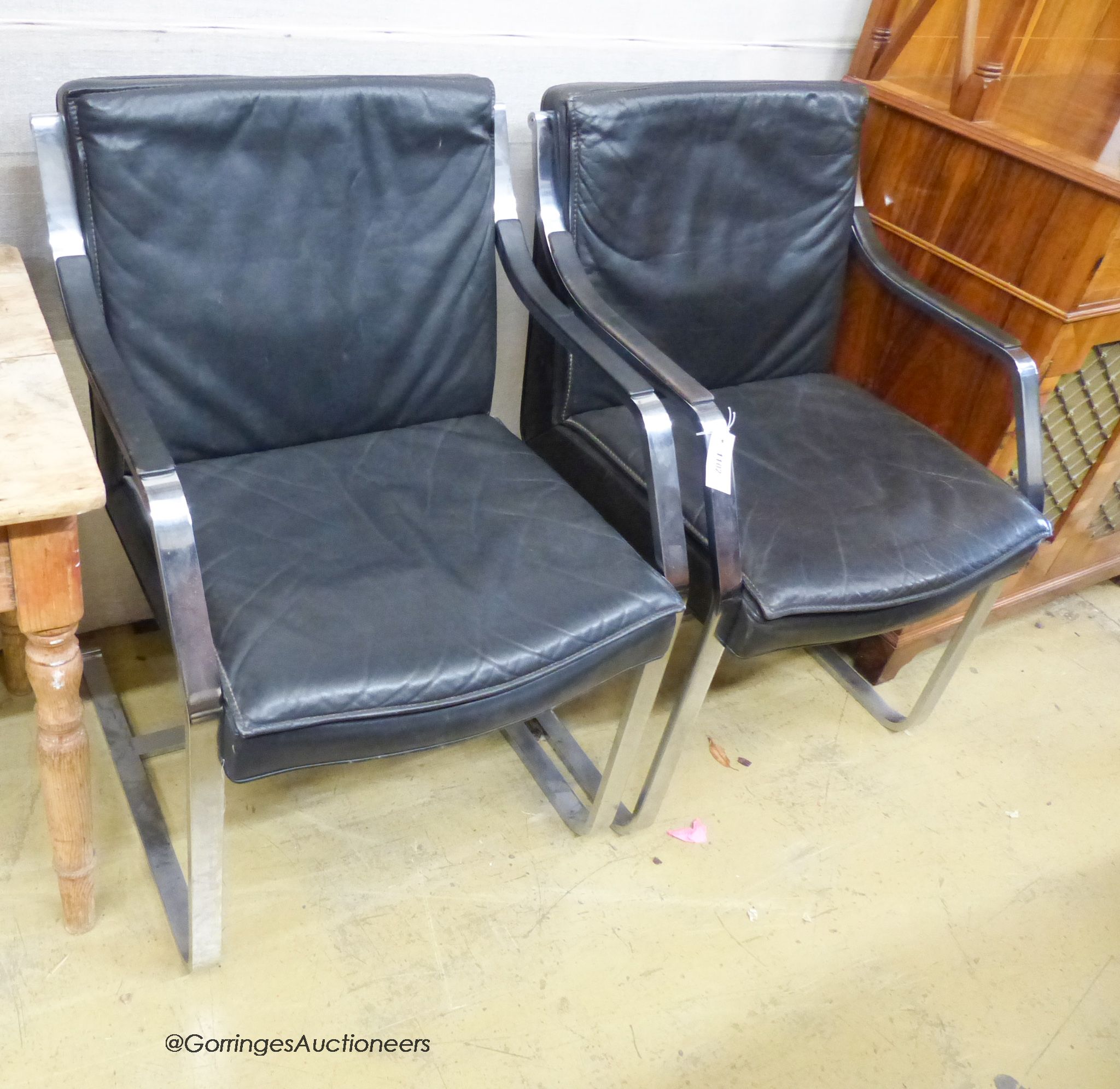 In the style of Knoll International. A pair of Mies Van deRohe design black leather and chrome cantilever chairs.